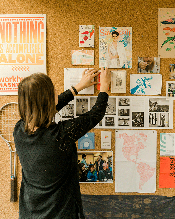 Photo of Focus Lab team member, Charisse, pinning something onto a cork board wall.